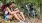 a man and woman sitting on a trail in the woods