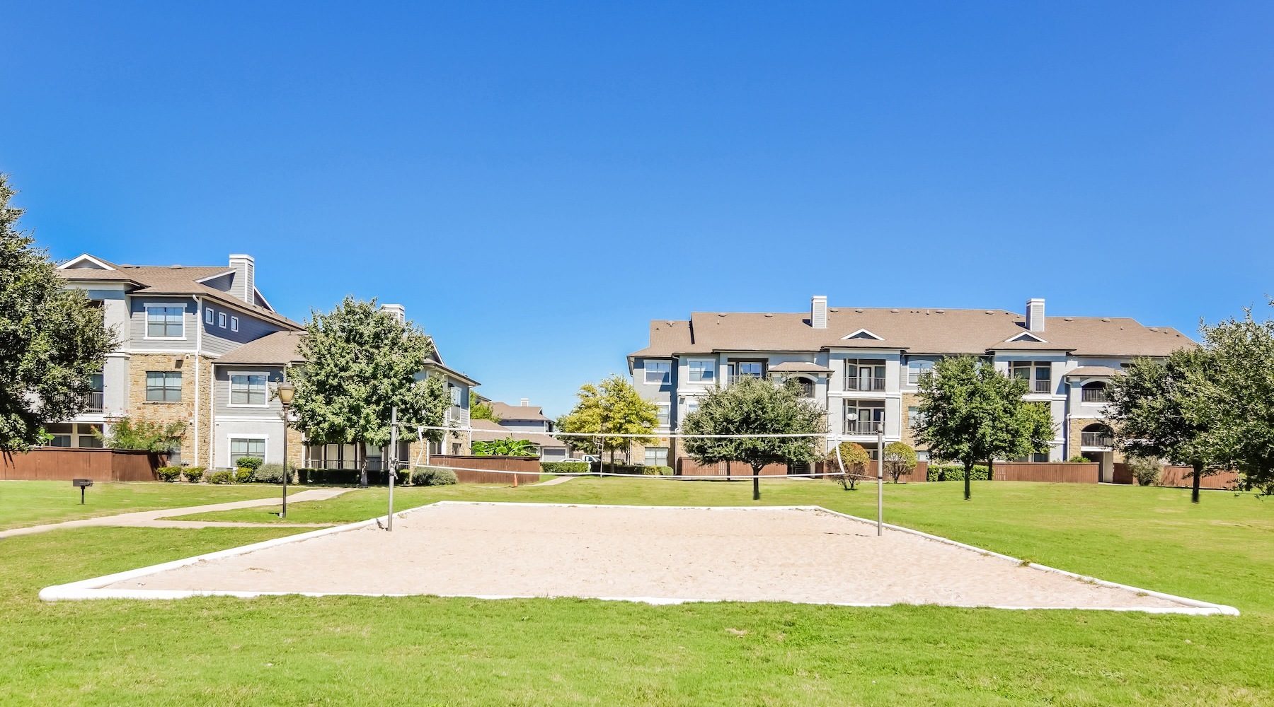 Access to resident only features sand volleyball court with a building behind it